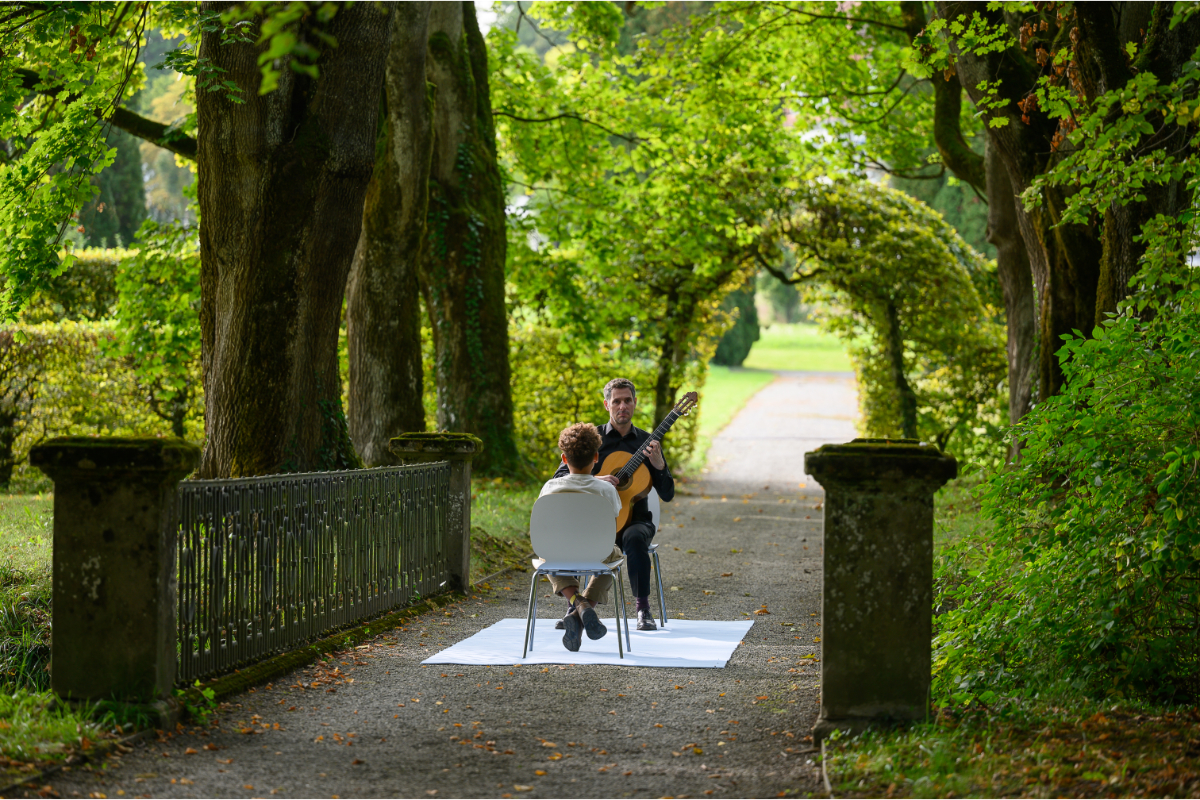Philipp Schmidt (Gitarre) spielt im Schlosspark für einen jungen Hörer.